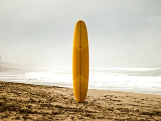 Gult surfebrett på sandstrand