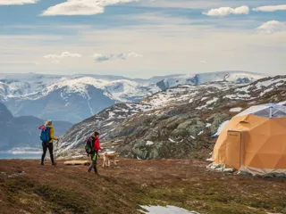 par går tur på toppen av et fjell med fjordutsikt og en dome