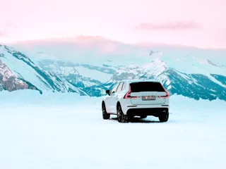 en hvit Volvo SUV i snø og fjelllandskap