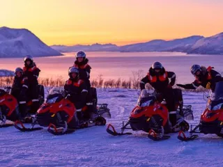 fire snøscootere med fører og passasjer med fjord og fjell i bakgrunnen