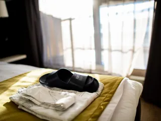 Slippers og håndkle ligger på en hotellseng