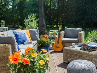 terrasse med rotting utemøbler, planter og en gitar