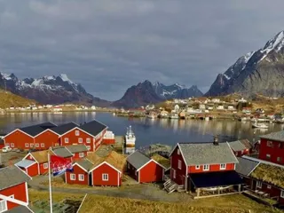 røde rorbuer ved havet i lofoten med fjellandskap i bakgrunnen