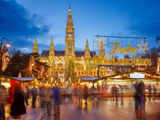 kveldsbilde av julemarked i Wien. Skilt med lys viser Frohe Weihnachten