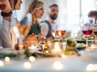 Nærbilde av bordpynt med lys og mennesker som spiser i bakgrunn