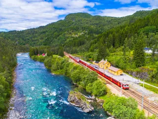 NSB-tog langs en elv i fjelllandskap sett fra luften 