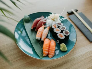 Tallerken med sushi biter og spisepinner på et trebord