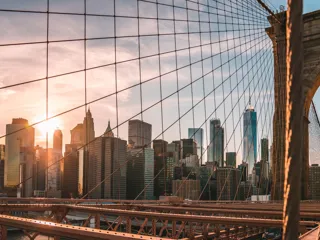 Solnedgang ved Brooklyn Bridge med skyskrapere i bakgrunnen