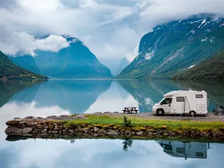 En bobil parkert ved en fjord med høye fjell