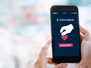 En hånd hålder en mobil hvor det står "e-donation" og "donate"